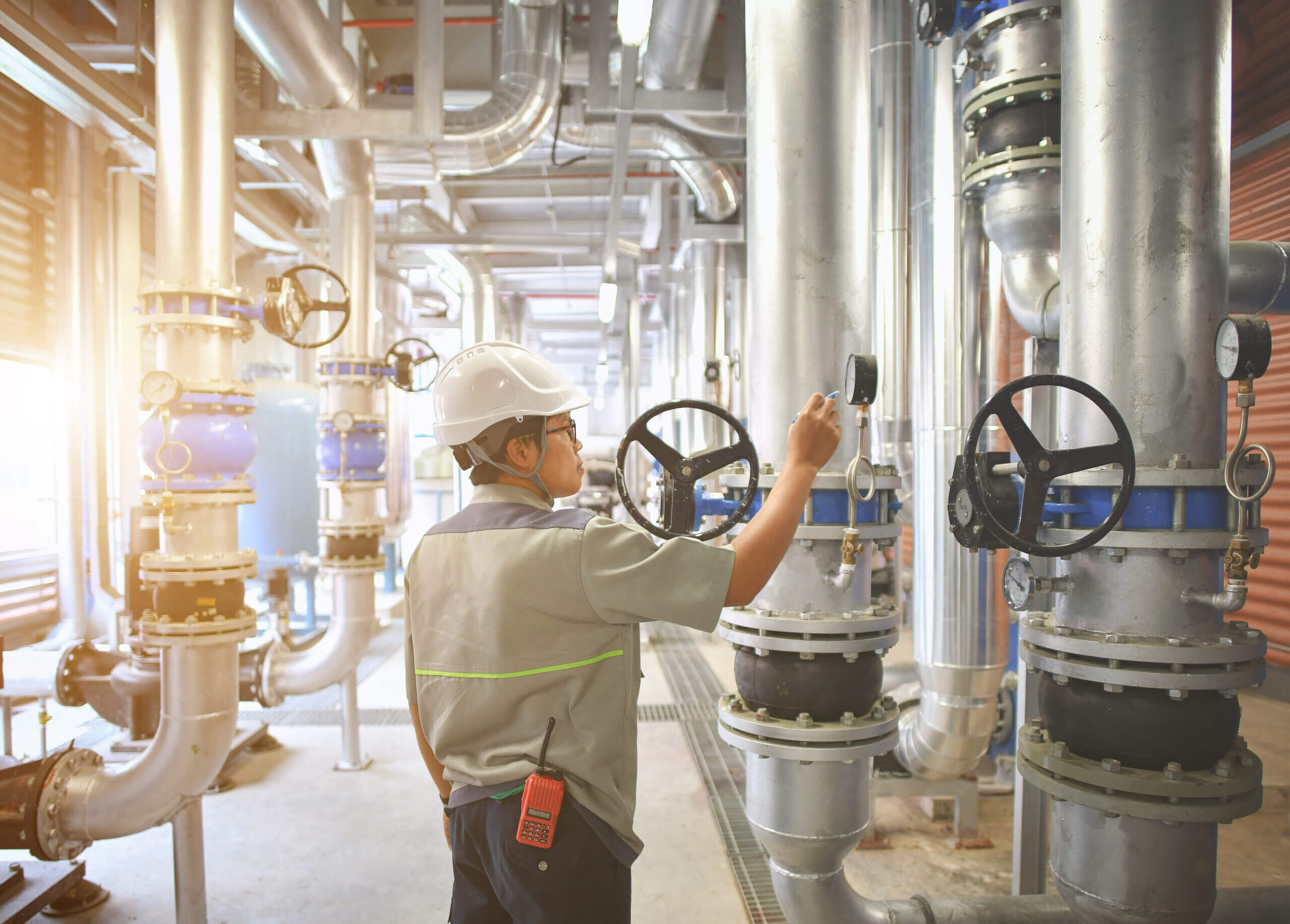 Engineer inspecting industrial HVAC piping system with pressure gauges and valves